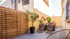 Une terrasse avec une clôture en bois, des plantes en pot et deux chaises longues.