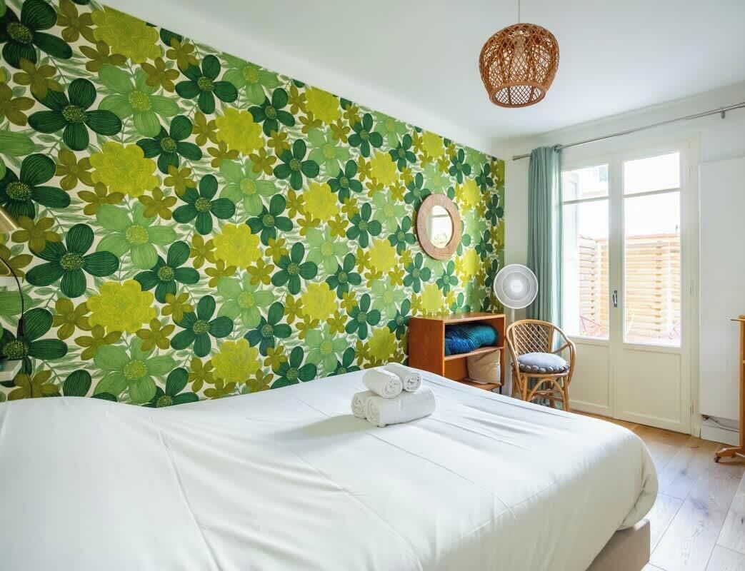 Ein Zimmer mit einem Bett, einem Sessel, einem runden Spiegel und einem Fenster.