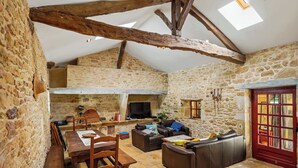 A rustic stone interior with a dining area, sofas, and a TV.