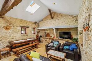 Un intérieur rustique en pierre avec une cheminée, des meubles en bois et un téléviseur.