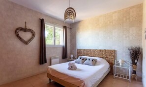 A bedroom with a bed, a heart-shaped decoration, a window, and a wall with a textured pattern. - La Terrasse d'Azur – Vue Mer, Jardin & Parking (La Palme)