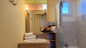 A bathroom with a sink, mirror, shower, and a vase of flowers. - Hillside Mediterranean Stay for 6 (Cerbère)