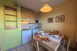 A compact kitchen with a dining area, a microwave, a sink, and a table set for breakfast.