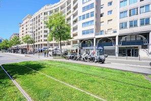 A multi-story building with a row of parked scooters, a sidewalk, and a grassy area. - Vue mer & terrasse 5 pers, proche plage et centre (Nice)