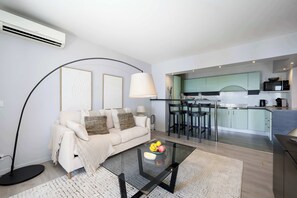 A modern living room with a glass coffee table, a sofa, and a kitchen in the background. - Vue mer & terrasse 5 pers, proche plage et centre (Nice)
