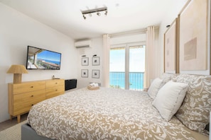 A bedroom with a bed, a wooden dresser, a television, and a balcony with a view. - Vue mer & terrasse 5 pers, proche plage et centre (Nice)