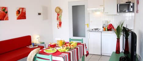 A compact living space with a dining area, kitchenette, and a red sofa.