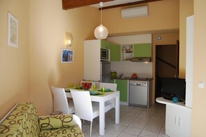 Cocina compacta con zona de comedor, que incluye una mesa blanca, sillas y una lámpara colgante.
