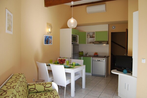Cocina compacta con zona de comedor, que incluye una mesa blanca, sillas y una lámpara colgante.