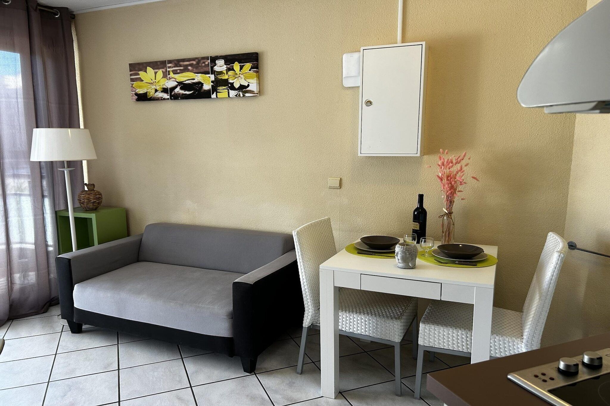 Un espacio habitable compacto con sofá, mesa de comedor, sillas, lámpara, cuadro y un armario.