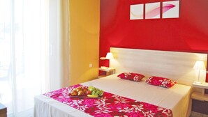 Ein Hotelzimmer mit Bett, Frühstückswagen, Nachttisch und einem Fenster mit Vorhängen.