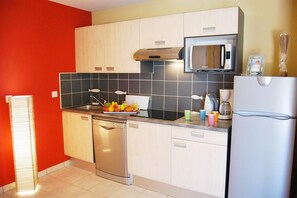 Eine Küche mit Geschirrspüler, Mikrowelle, Kühlschrank und Spüle.