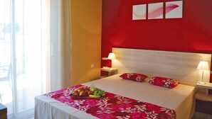 Une chambre d’hôtel avec un lit, deux lampes de chevet, une fenêtre avec des rideaux et un plateau de nourriture posé sur le lit.
