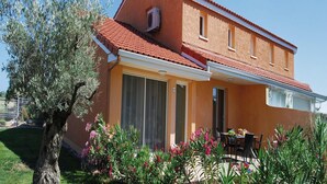 Un bâtiment à deux étages, doté d’un toit recouvert de tuiles rouges, de grandes fenêtres et d’un patio abrité.