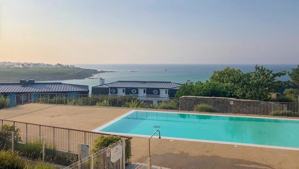 Una piscina con vistas al mar, rodeada de edificios con techo metálico.