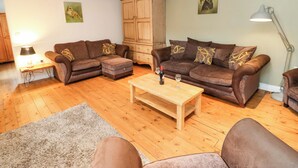 A living room with a brown sofa set, wooden cabinet, and a coffee table. - The Hay Barn (Ripon)