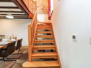 Eine Holztreppe führt zu einem Schlafzimmer auf dem Dachboden, darunter befindet sich eine Essecke.