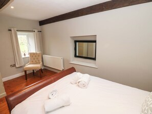 Quarto com uma cama grande, uma cadeira, uma janela e um radiador.