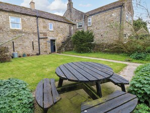 A stone building with a grassy yard, a wooden table, and a bench. - The Hay Barn (Ripon)