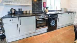 A modern kitchen with a built-in oven, dishwasher, and a coffee machine. - The Hay Barn (Ripon)