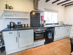 A modern kitchen with a built-in oven, dishwasher, and a coffee machine. - The Hay Barn (Ripon)