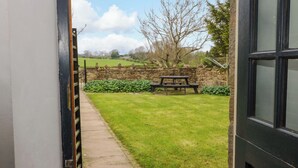 A pathway leading to a stone wall and a picnic table in a grassy area. - The Hay Barn (Ripon)