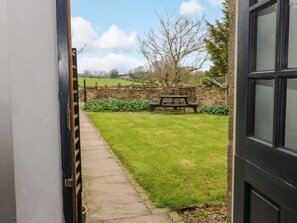 A pathway leading to a stone wall and a picnic table in a grassy area. - The Hay Barn (Ripon)
