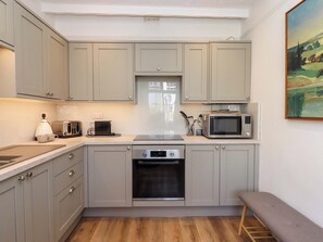 A kitchen with grey cabinets, a microwave, a toaster, and a dishwasher. - Kents Cottage (Torquay)