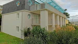 A two-story building with a balcony, a circular window, and a small garden area. - Family Escape near Trescadec (Audierne)