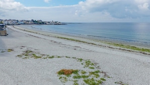 A beach with a clear view of the sea, a sandy shore, and a distant town. - Family Escape near Trescadec (Audierne)