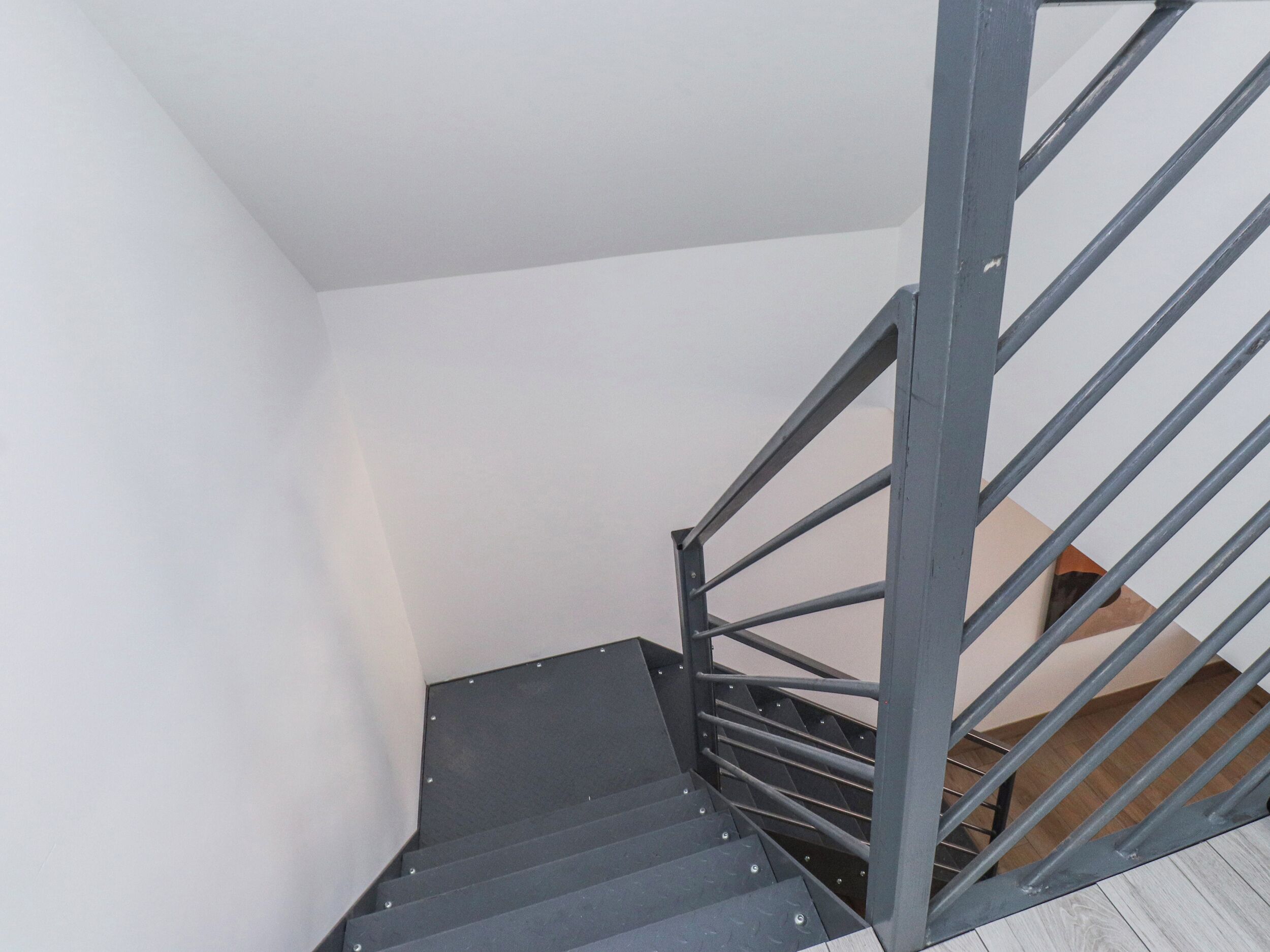 Una escalera con barandillas de metal y piso de madera.