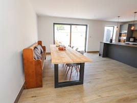 Una cocina moderna con una mesa y banco de madera, una puerta corrediza de vidrio y una pequeña isla con pileta.