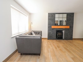 Una sala de estar moderna con un sofá gris, una chimenea y un ventanal con persianas.