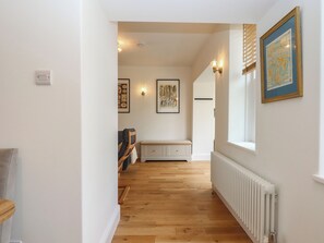 A hallway with wooden flooring, a radiator, and a bench. - Hares Cottage (Torquay)