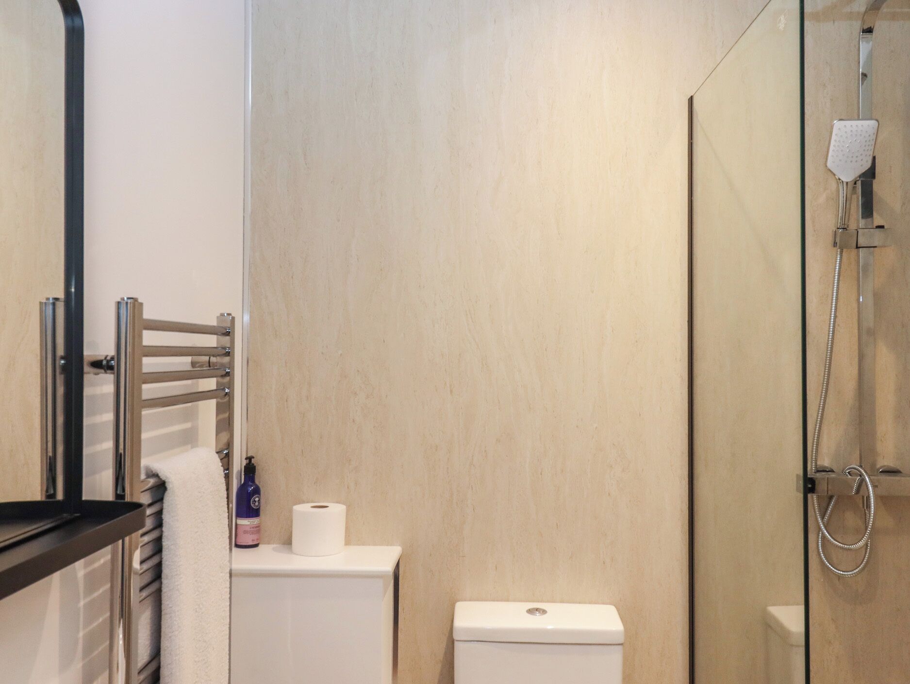 A bathroom with a toilet, a towel rack, and a shower.