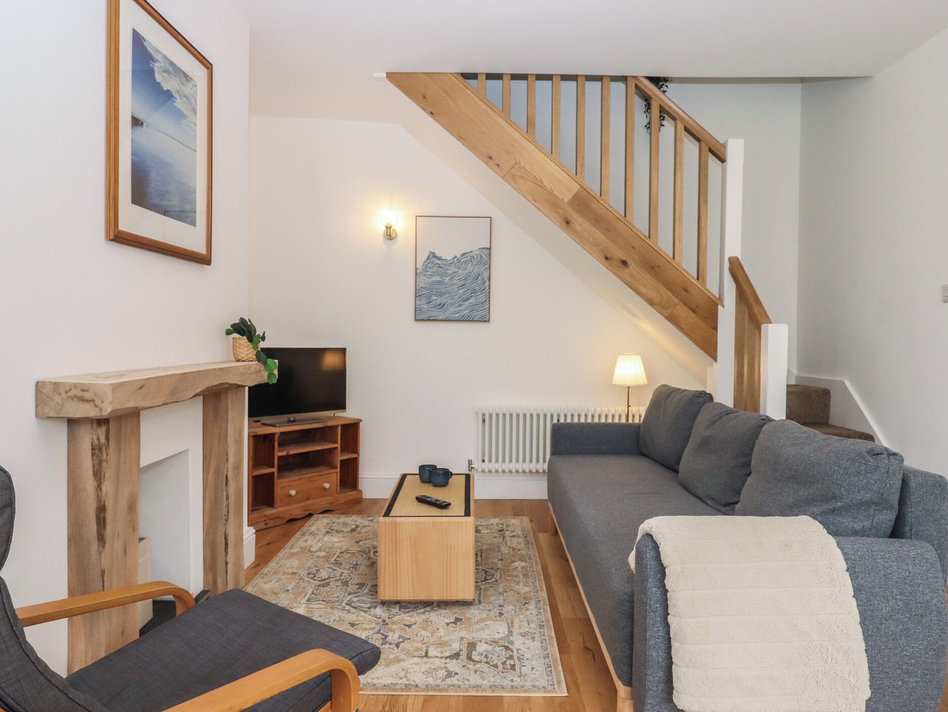 A living room with a wooden staircase, a sofa, a coffee table, a TV, and a fireplace.