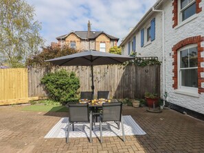 Eine Terrasse im Freien mit Tisch und Stühlen, einem Holzzaun und einem Haus im Hintergrund.