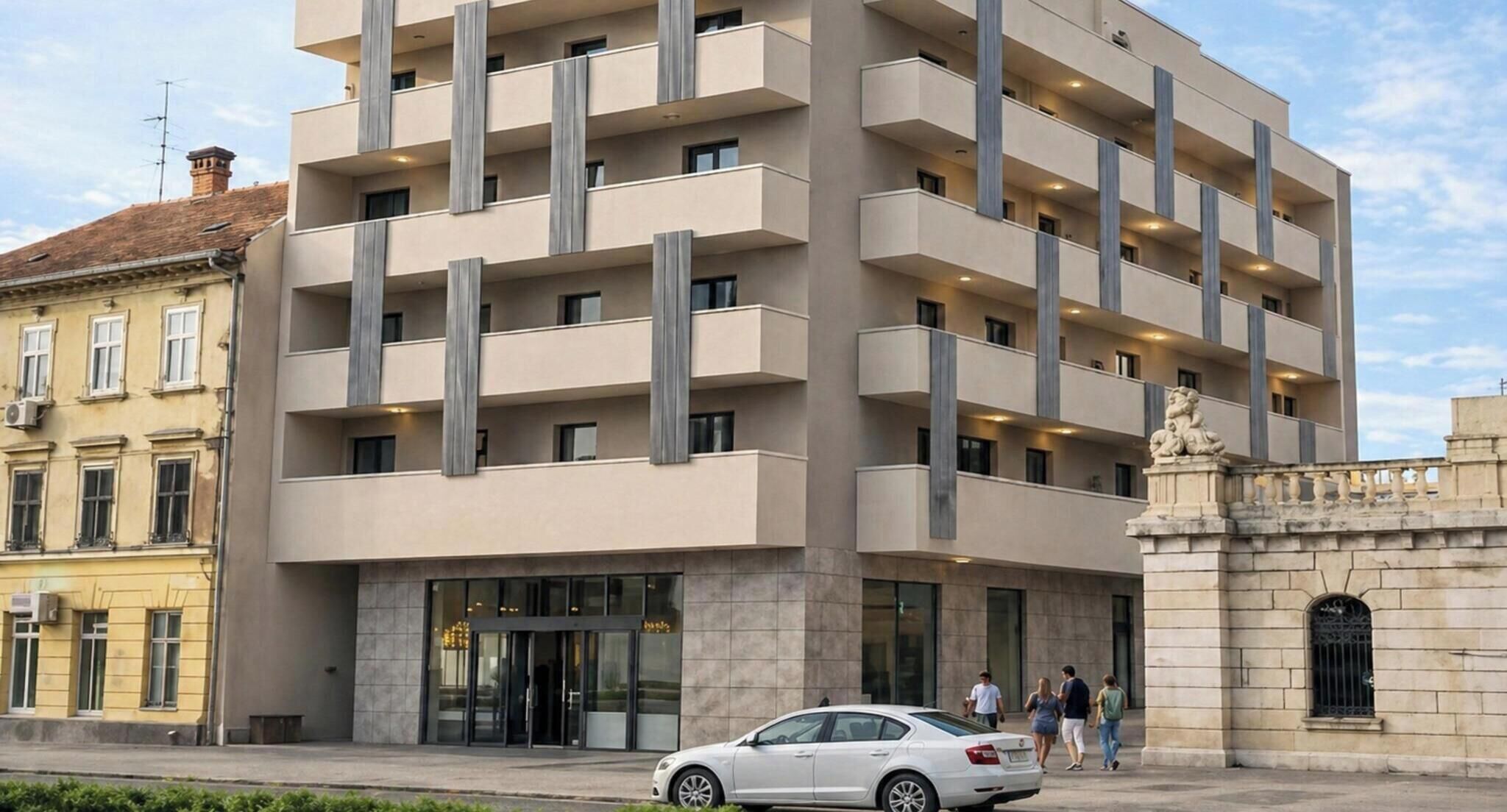 A multi-story hotel with a modern design, featuring balconies, a central entrance, and a stone facade.