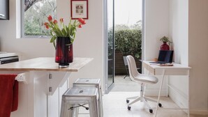 Eine moderne Küche mit einer Holzausziehtheke, einer roten Vase mit Blumen, einem gerahmten Bild an der Wand und einer Glastür zum Balkon.