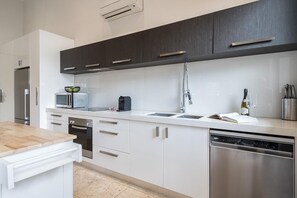 Een moderne keuken met witte kastjes, roestvrijstalen apparatuur en een houten aanrecht.