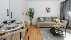 Sala de estar moderna com uma mesa de jantar, sofá e uma planta em vaso.