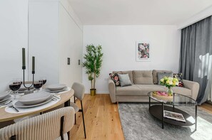 Ein modernes Wohnzimmer mit Esstisch, Sofa und einer Topfpflanze.