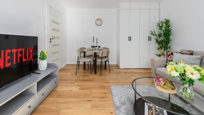 Uma sala de estar moderna com televisão de tela plana, área de refeições e sofá.