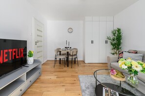 Ein modernes Wohnzimmer mit Flachbildfernseher, Essbereich und einer Couch.