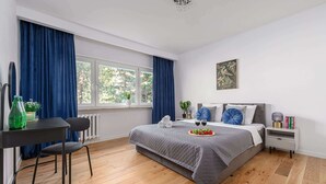Quarto moderno com cama, mesa de cabeceira e janela com cortinas.