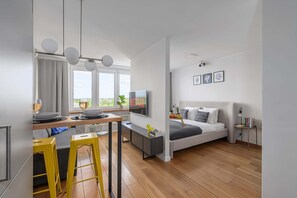 A modern apartment with a kitchen, dining area, and a bedroom with a bed, bedside table, and a TV. - Lumina apart near the Visla embankment (Warszawa)