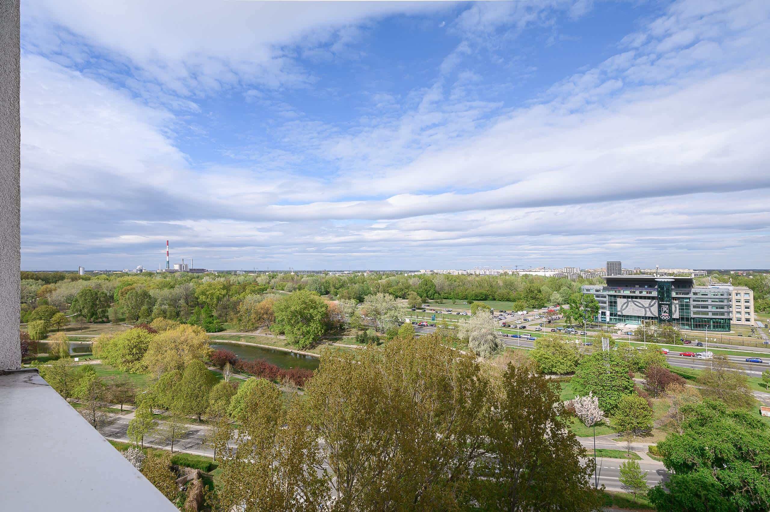 Une vue urbaine comprenant un parc, un bâtiment moderne et une tour située au loin.