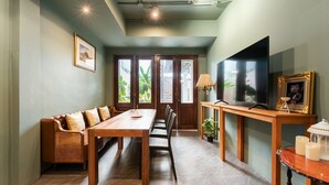 Una habitación con una mesa de comedor de madera, un sofá, un televisor y una lámpara.