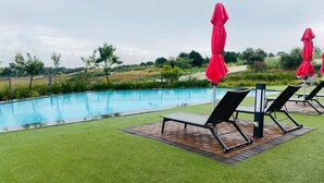 A swimming pool with lounge chairs and red umbrellas.