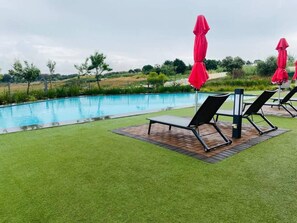 A swimming pool with lounge chairs and red umbrellas. - The Modern Sanctuary (Boksburg)